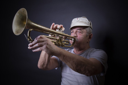 mature man posing with trombone in front of portrait backdropの写真素材