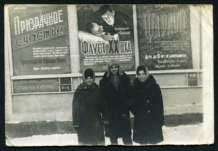 USSR - CIRCA 1980s: An antique photo shows three people on a background of theater postersのeditorial素材