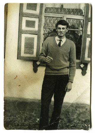 Ussr - CIRCA 1980s: An antique Black & White photo show Young man standing near the windowのeditorial素材