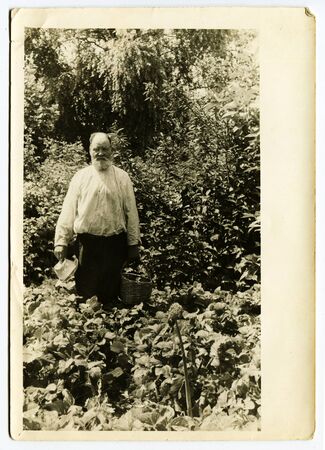 Ussr - CIRCA 1980s: An antique Black & White photo show bearded grandfather standing in the garden...