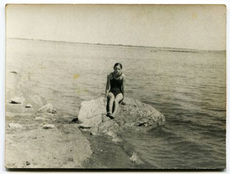 USSR - CIRCA 1960s: An antique photo shows  girl on a rock near the sea, USSR, circa 1960sのeditorial素材