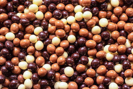 Chocolate covered nuts in different colors. close-up on the bench.の写真素材