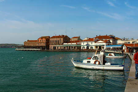 The boat anchored in the harbor. Historical buildings near the harbor. Small cafes.の写真素材