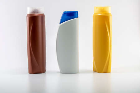 Shampoo, moisturizing bottles in brown, white, yellow colors. Shooting in white background. With blue cap in the middleの写真素材