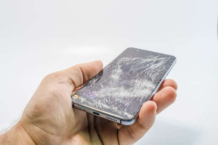 Broken glass mobile phone. It stands in your hand. White background.の写真素材