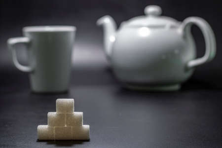 ahead of sugar cube and porcelain mug in background and teapotの写真素材