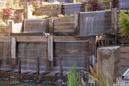 Decorative waterfall flowing from high. Inside the park. The board is furnished. Trees in the background.の写真素材