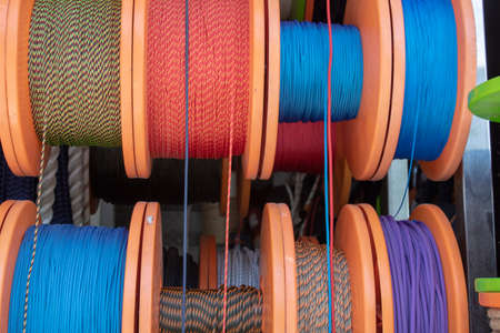 Side shot of the strings wrapped around the spool. Ropes in white, blue, red, yellow colors....
