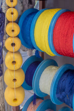 Side shot of the strings wrapped around the spool. Ropes in white, blue, red, yellow colors....