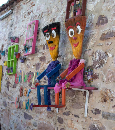 Colorful frames hanging on the wall. Flowerpots placed in the frame. They have evil eye beads.It was taken on the island of Cunda in Ayvalik.Human figures made of broom.の写真素材