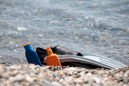 Flippers on pebble stones near sea. Suncreamの写真素材