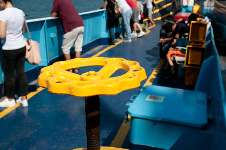 Yellow valve in ship and people sitting and watching the sea in background. Photographed on the steamer.の写真素材