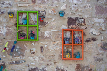 Colorful frames hanging on the wall. Flowerpots placed in the frame. They have evil eye beads.の写真素材