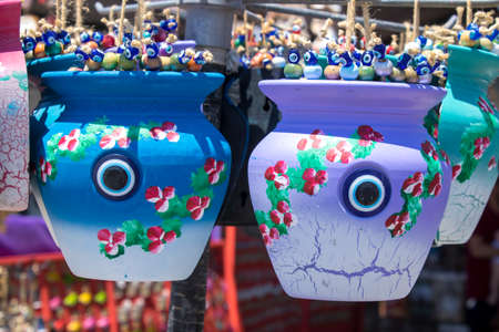 Decorative colorful small buckets sold in the store. Yellow color hanging with ropes. There are evil eye beads inside.の写真素材
