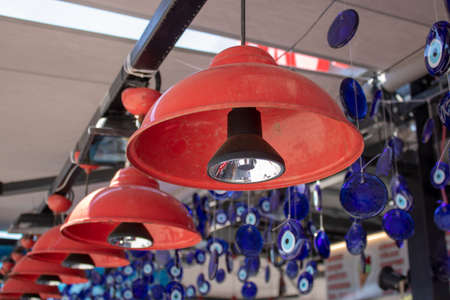Red lightings hanging in front of store. Conical shape. Evil eye beads are in the background.の写真素材