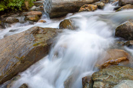 Close-up and long exposure of water flowing through rocks. Foggy imageの写真素材