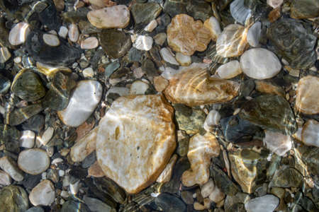 Round stones close-up in the water. Etching of water