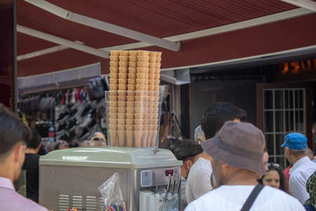 In the street full of people. Basket of cones on ice cream machine.のeditorial素材