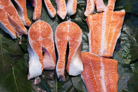 Pieces and fillet of salmon to portions on ice in supermarket. Sale of seafood, fish. Open showcases , counter of seafood marketの写真素材