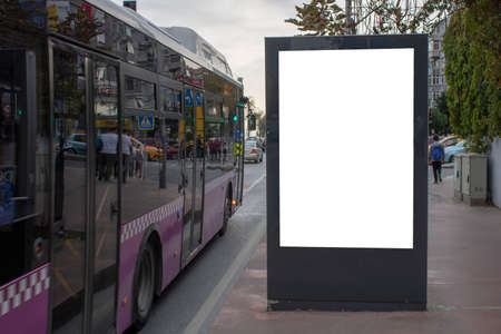 Blank white rectangular billboard at the roadside. Vehicles pass through the asphalt road.の写真素材