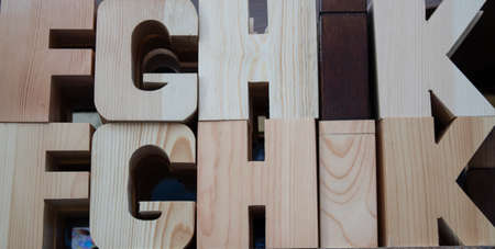 Wooden letters in dark coffee color. Can be used for decoration and educational purposes. The photo was taken on the bench.の写真素材