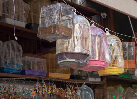 Empty sale bird cages. They have different colors and designs. Photo was taken in front of the store.の写真素材
