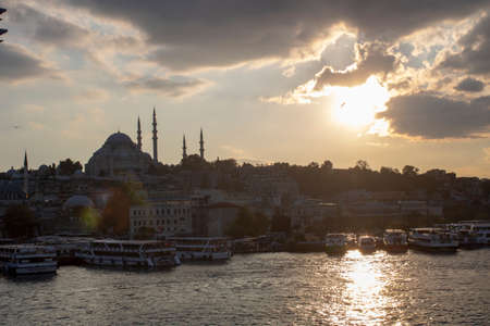 Suleymaniye Mosque and Eminonu coast in cloudy weather. Boats selling fried fish and people walking around. Photographed towards the evening.のeditorial素材