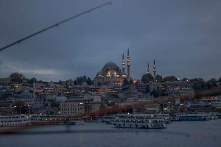 Suleymaniye Mosque and Eminonu coast in cloudy weather. Boats selling fried fish and people walking around. Photographed towards the evening.のeditorial素材