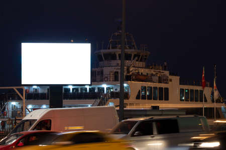 Advertising sign is blank white. Signage is across the road. There is a ferry in the back.の写真素材