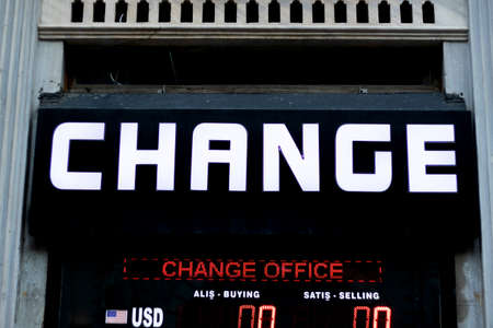 Signpost belonging to the exchange office. Close-up. White text on black signboard.の写真素材