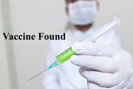 He is holding a coronavirus vaccine. The vaccine is green. On the left says vaccine found.の写真素材