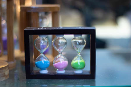 Hourglass close-up in 3 different colors. On the glass table.の写真素材