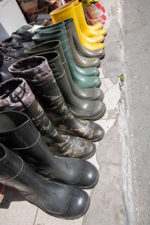 Rubber boots photographed on the pavement. It has yellow and dark green colors.の写真素材