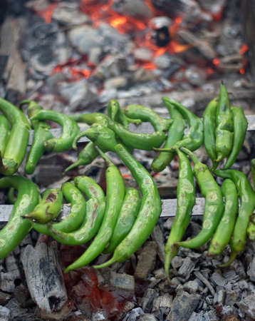 Green peppers with bottles on the grill. The embers grilled in charcoal under it is very hot. Closeup.の写真素材