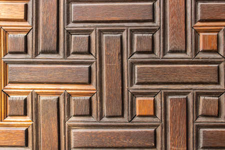 Old wooden door with geometric pattern. Wooden surface is tinted in warm color.
