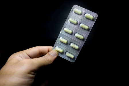 Yellow round pills in a package on a black background, close-up
