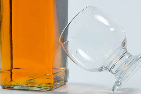 Whiskey bottle and cross-standing glass based on the bottle. The photo was taken on white background...