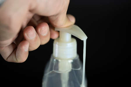 A hand pushing the button of the liquid soap bottle. Hand sanitizer against germs and viruses. The photo was taken while liquid soap was flowing.の写真素材