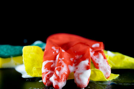 Scouring sponge foaming gloves and yellow cleaning cloth. In black background. Close up.の写真素材