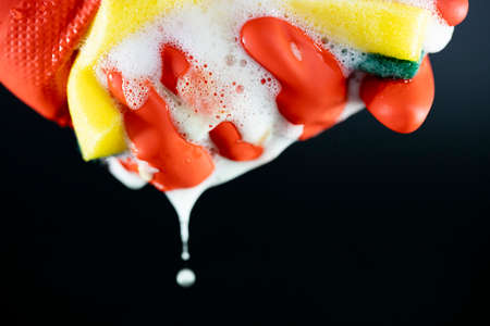 Scouring sponge foaming gloves and yellow cleaning cloth. In black background. Clse up.
