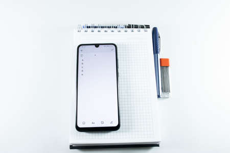 Concept of notepad phone pen. The photo was taken on white background and studio.の写真素材