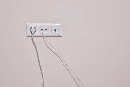 Electrical telephone and television antenna socket. Close-up. The phone and power cord are plugged in.の写真素材