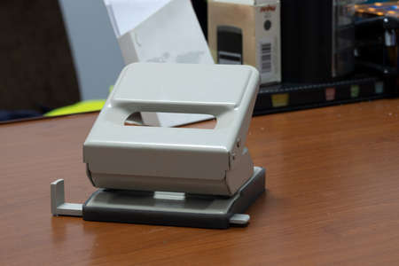 Close up of colorful paper hole punch on white. On a brown office desk.の写真素材