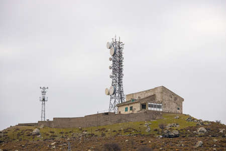 A base station in the field. Mobile Phone communication station. On a long pole on a high hill. Photo was taken on cloudy winter day.の写真素材