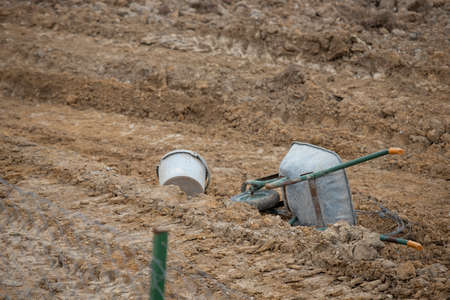 An overturned wheelbarrow and bucket on the farmland. A photo was taken from behind.の写真素材