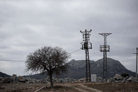 Power lines and transformers. There is a tree on the left and the weather is cloudy. Photographed in the winter. Gokceada, Turkey.の写真素材