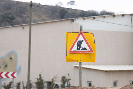 The excavation sign was photographed by a roadside in red, white and yellow. There is a building in the background.の写真素材