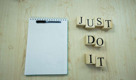 There is a notepad checker and pencil on the table. On the right, it says, Just do it, with a wooden...