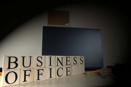 Text of business office on wooden cubes in front of office desk. There are laptop and office supplies on the table. Consept and studio.の写真素材