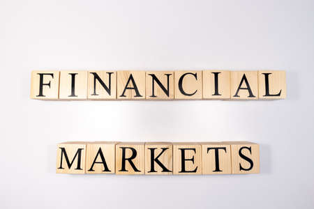 financial market concept - text FINANCIAL written on wooden blocks with downward stack of coinsの写真素材
